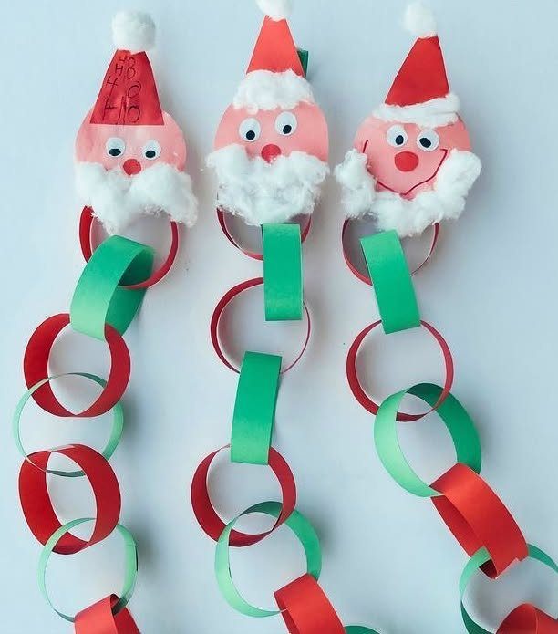 Three red and green paper chain garlands decorated with handmade Santa Claus faces on a white background.