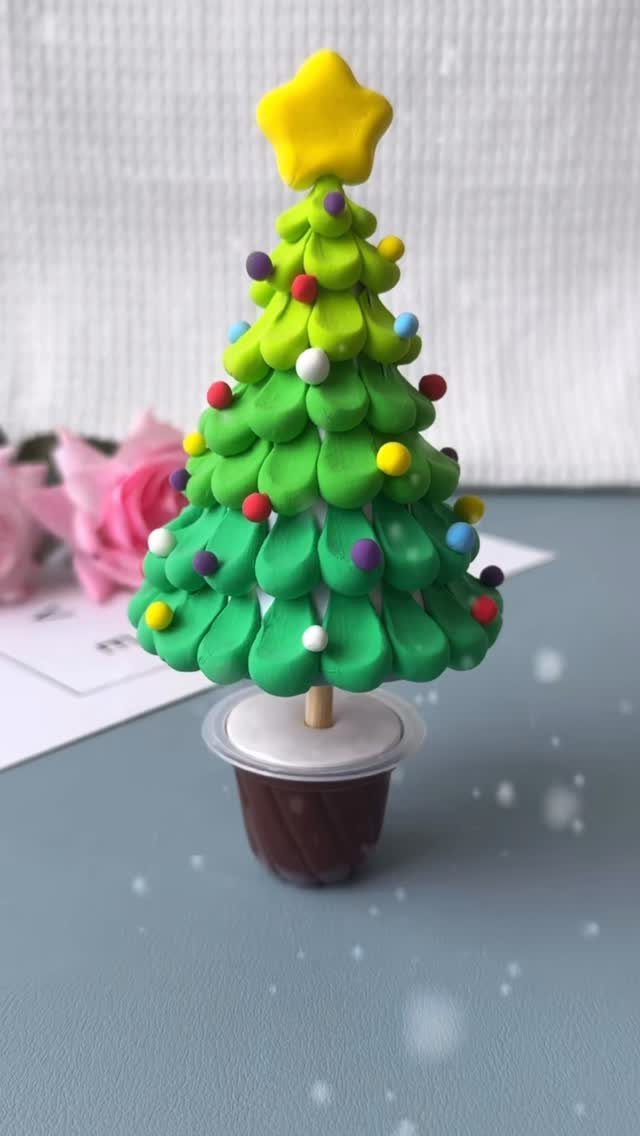 A handmade green clay Christmas tree decorated with colorful ornaments and a yellow star topper.