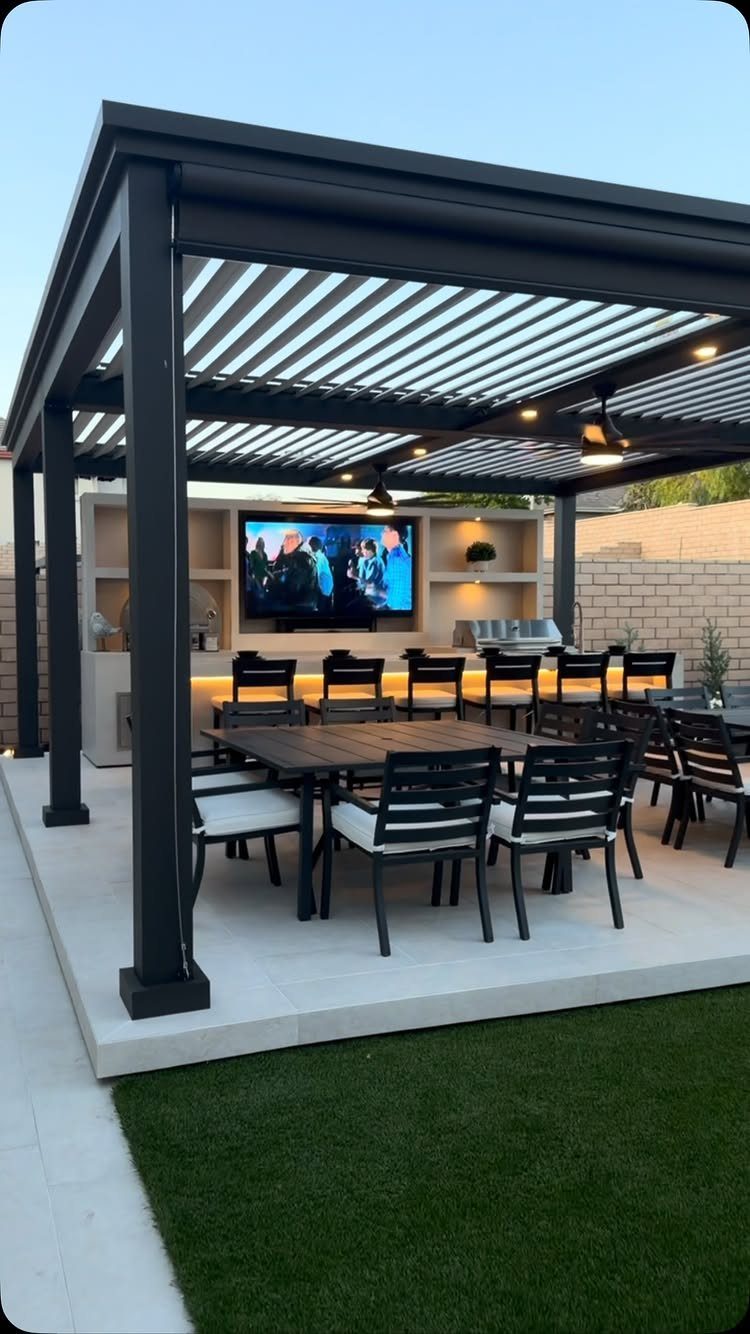 11 Outdoor Kitchen with Pool Ideas That Actually Work 7 Modern black pergola covering an outdoor kitchen with a television, dining table, and built-in appliances.
