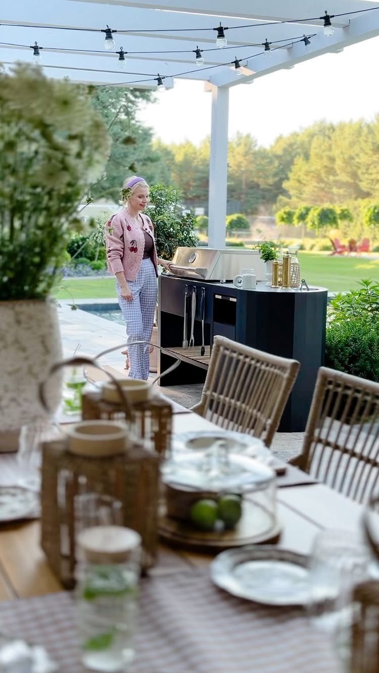 11 Outdoor Kitchen with Pool Ideas That Actually Work 11 Modern black outdoor kitchen unit with a grill situated near a swimming pool and lush greenery.