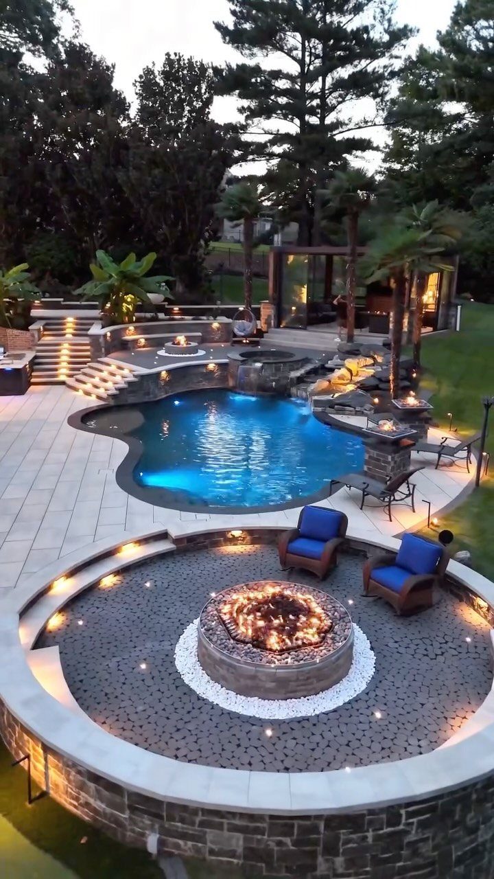 11 Outdoor Kitchen with Pool Ideas That Actually Work 8 A luxury backyard featuring a glowing swimming pool, stone fire pit, and outdoor lounge area.