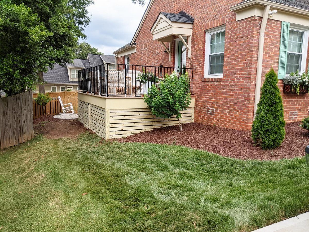 3 Room Under Deck Ideas for Leftover Space 1 A wooden deck with horizontal light-colored slats used as skirting against a brick house.