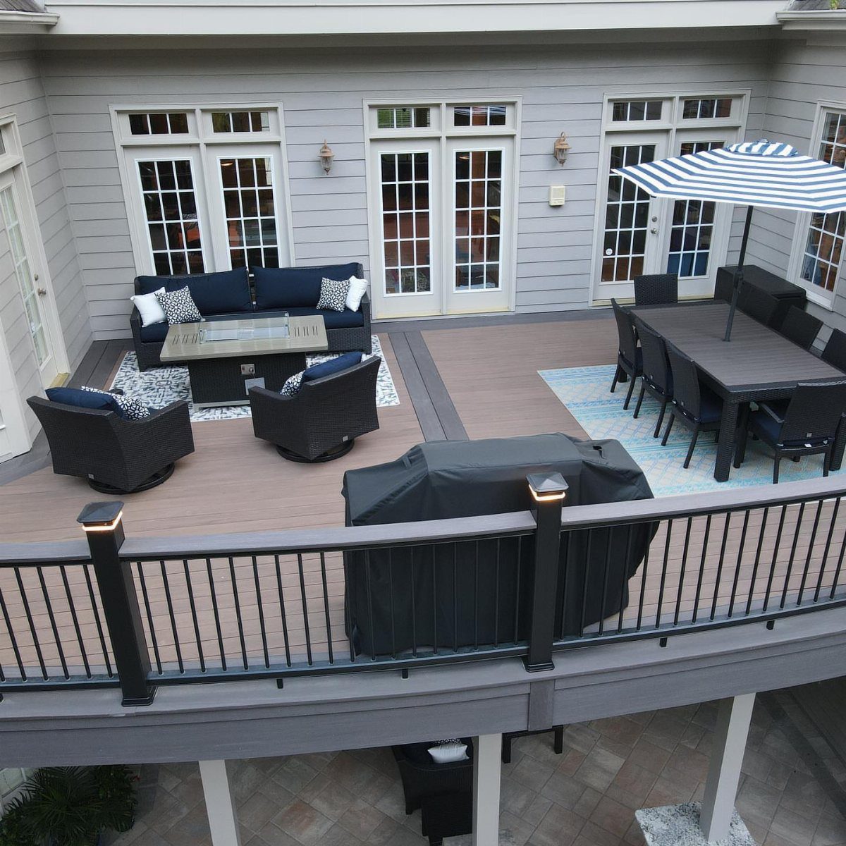 A large wooden deck divided into a lounge area and a dining area with an umbrella.