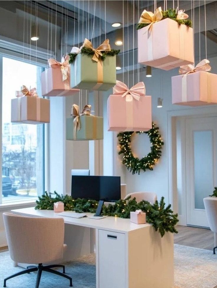 Hanging pink and mint gift boxes above a decorated white office desk with pine garlands.