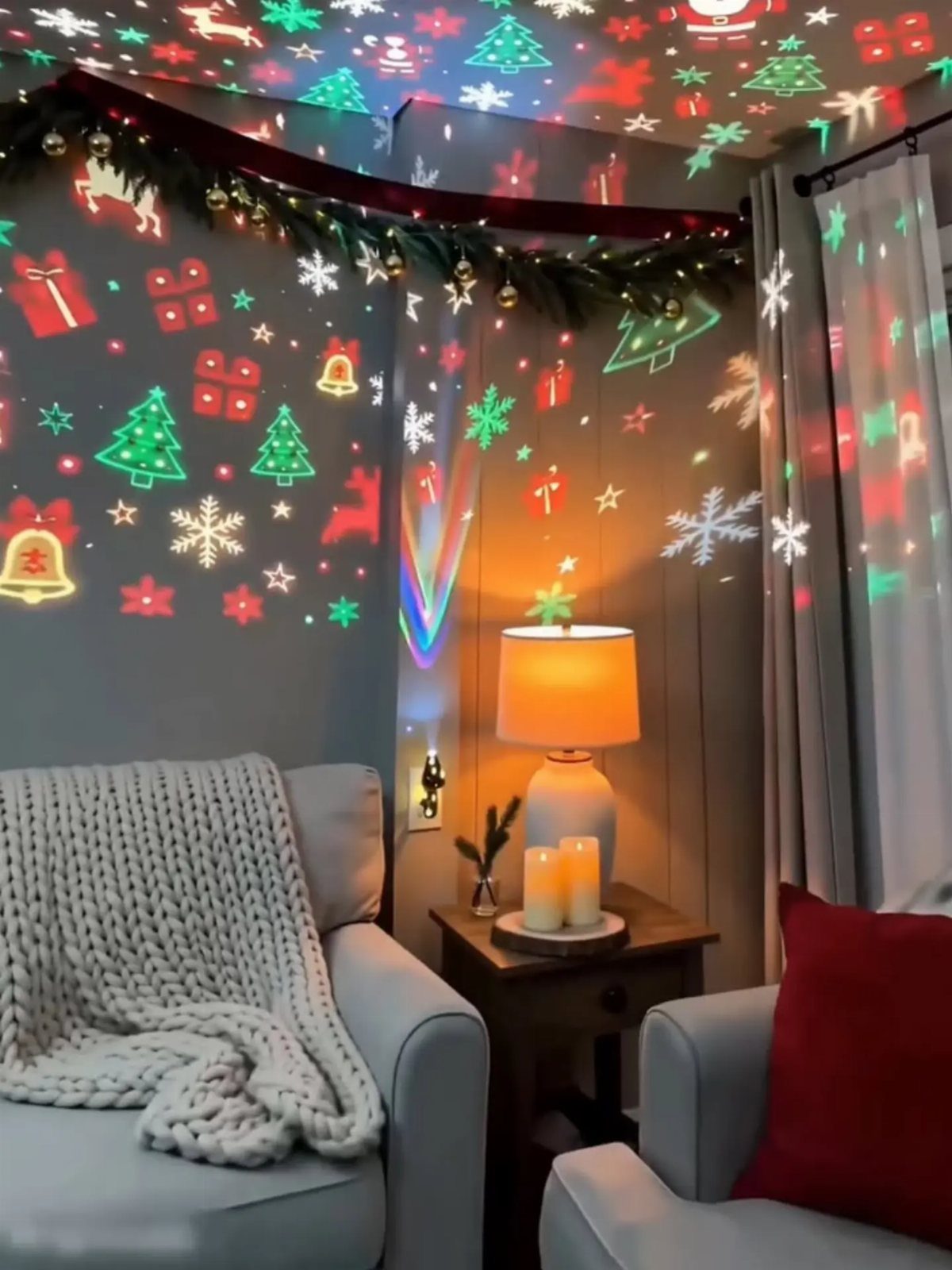 Living room corner with armchairs and colorful Christmas light projections on the walls.