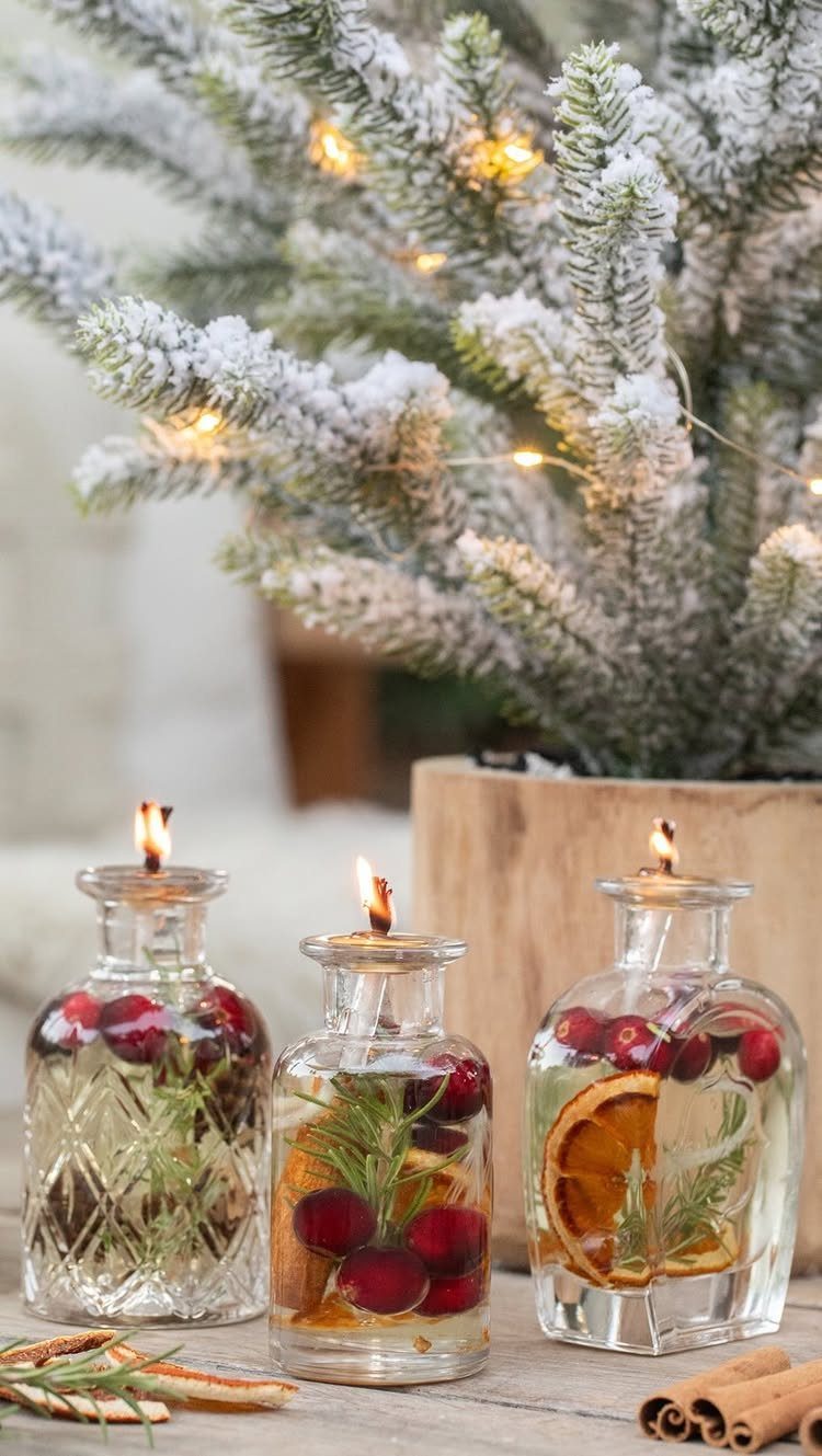 Three glass bottles filled with water, cranberries, rosemary, and orange slices acting as candles.